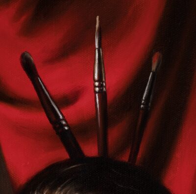 Detail of paintbrushes tucked in hair against a red drapery on oil painting